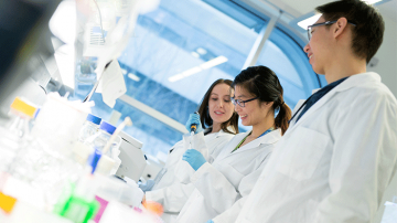 Smiling researchers wearing labcoats in a lab