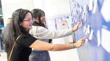 Smiling people interact with a wall of sticky notes